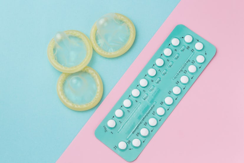 Contraceptive pills and condoms on colored background. View from above. Concept of birth control