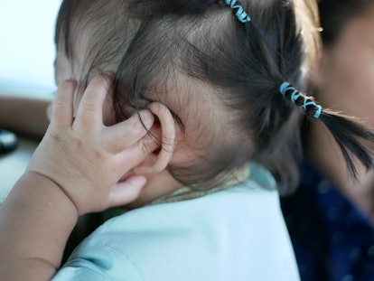Little Asian baby girl, 14 months old, keeps pulling on, pushing her finger into her ear, and scratc...