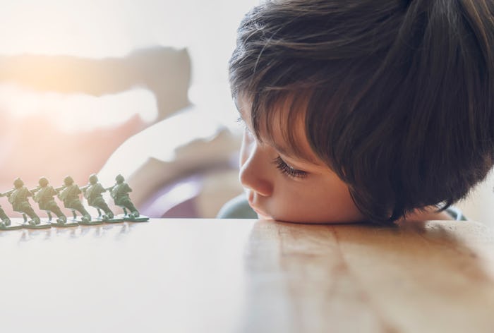 High key light portrait of lonly kid boy with sad face playing alone, Bored Child lying head donw on...
