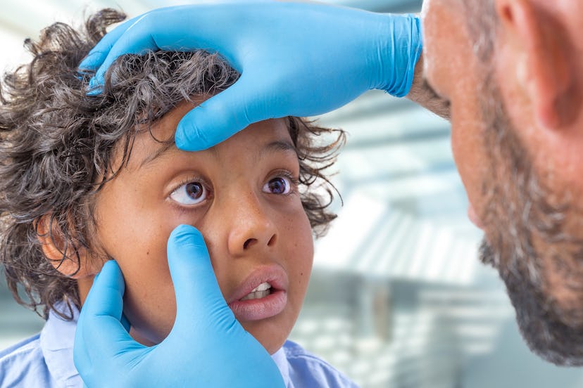 male ophthalmologist doctor examining teen boy patient eyes determining color blindness in toddlers ...