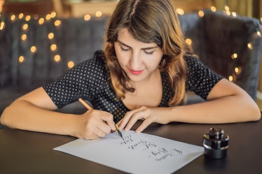 dream big set goals take action. Calligrapher Young Woman writes phrase on white paper. Inscribing o...