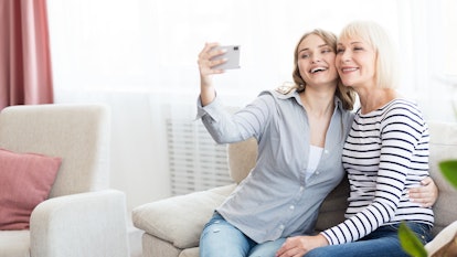 Senior mom and her daughter doing selfie using smartphone and smiling, copy space