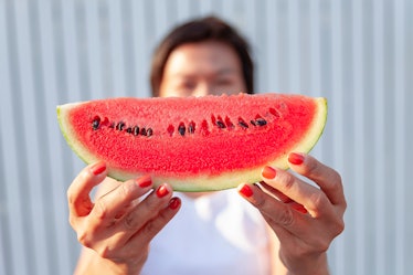 A playful woman holding a watermelon slices with a smile with a happy smile. On a bright day. Is a h...