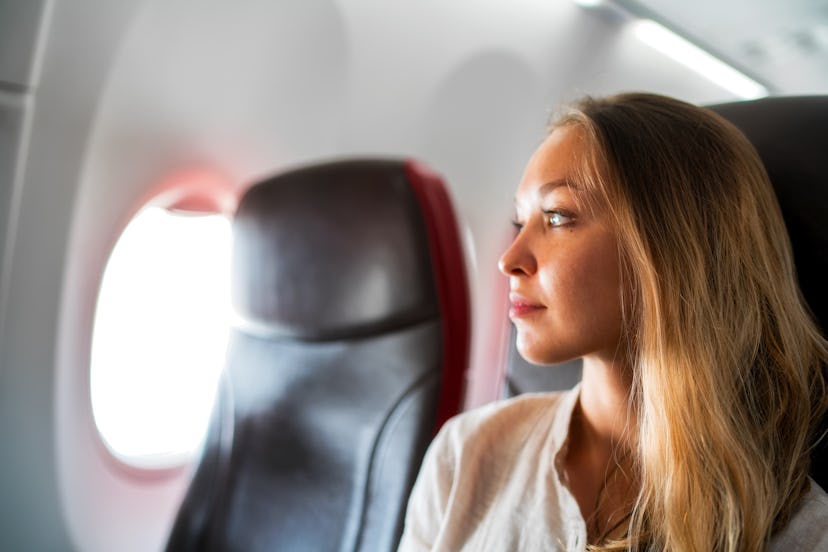 Portrait of young relaxed woman in plane looking to the window