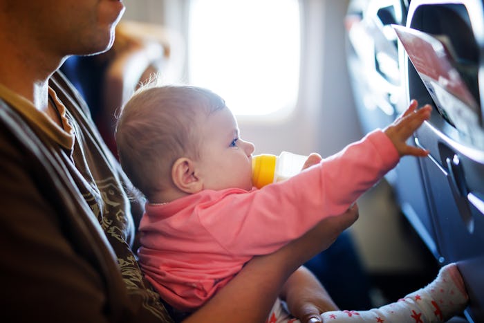 Father holding his baby daughter during flight on airplane going on vacations