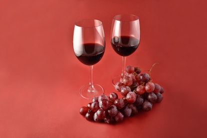 Red wine with grapes stock images. Two glasses of red wine. Red wine on a red background