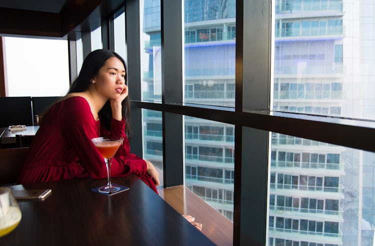 Pensive girl having a drink alone in a bar