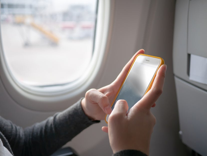 A woman passenger using  yellow mobile phone on the airplane while traveling