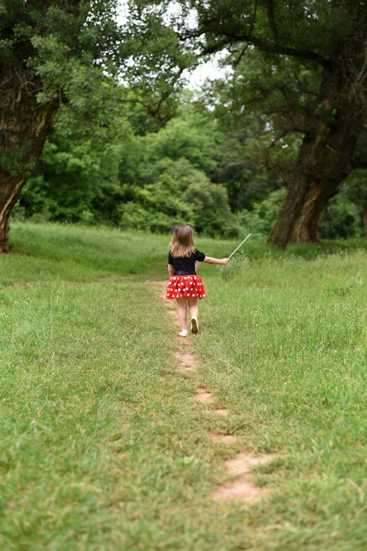 Little girl is walking in the woods. Child in red