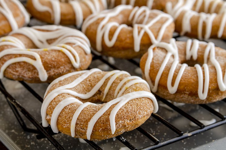 Close up of homemade baked cinnamon  pumpkin donuts sitting on wire rack waiting for apple cider dri...