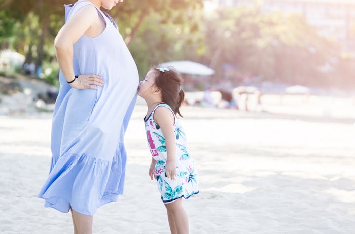 photo of Happy family. Pregnant mother and daughter kissing relaxing and playing on the beach,Happy ...