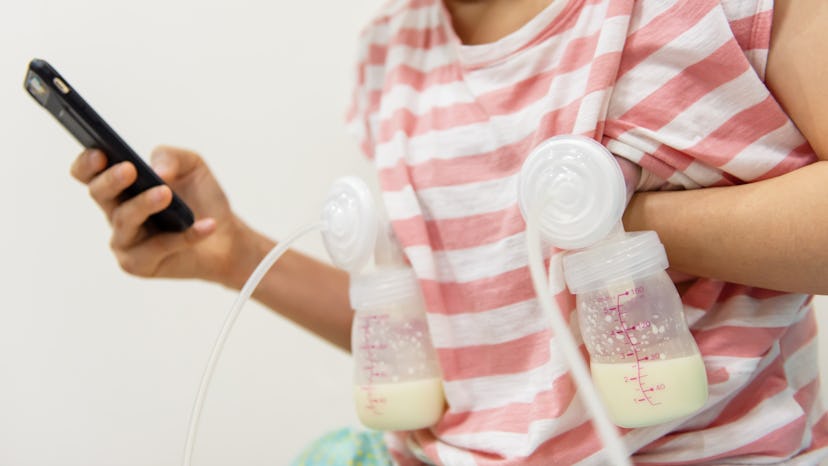 Mother pumping milk to bottles by Automatic breast pump machine while play social media, chat, and s...