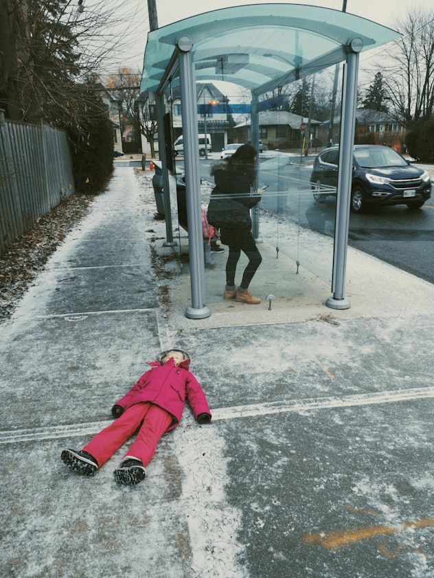 Child kid in tantrum bad mood lying on ground in city outside street not willing to obey parents. Pa...