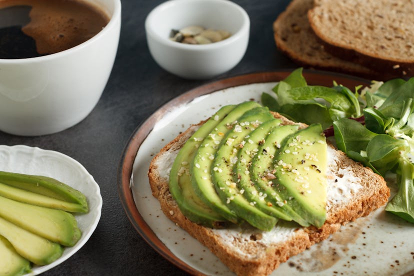 Avocado sandwich on dark rye toast bread made with fresh sliced avocado,  cream cheese and seeds, fr...