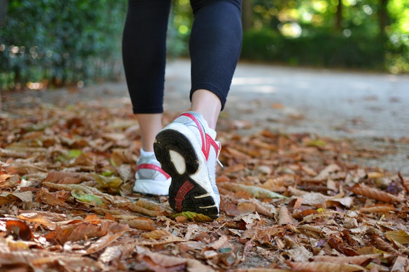 Woman walking on the fallen leaves of autumn