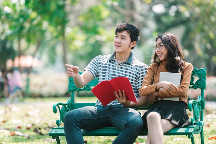 Girl friend and boy friend leaning knowledge by book while there are sitting in the park  