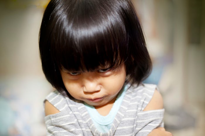 Portrait image of little Asian baby girl gets really angry, looking up to camera