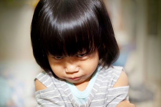 Portrait image of little Asian baby girl gets really angry, looking up to camera