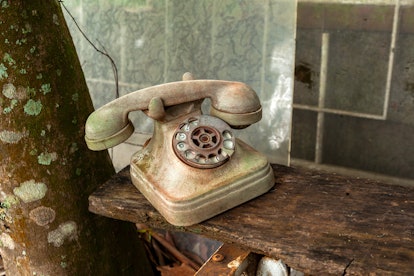 Old dirt broken abandoned disk telephone - no communication offline rusty
