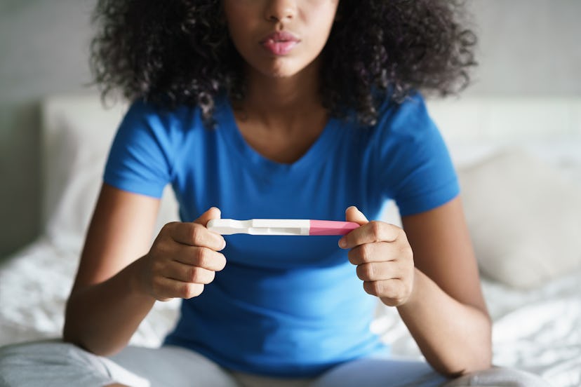 woman on bed looking at pregnancy test result