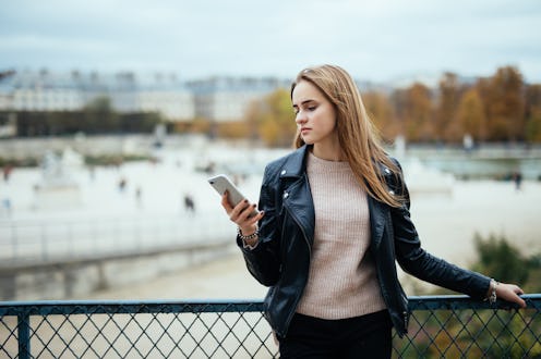 Woman texting on the smart phone walking in the street