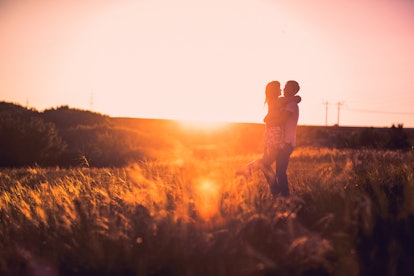 Romantic couple standing  and kissing on background summer meadow sunset