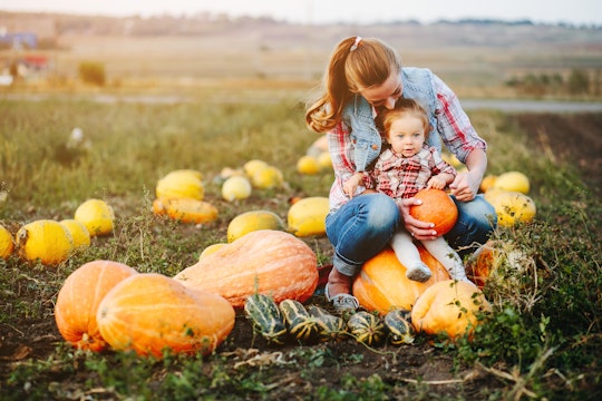 Mother and daughter sitting on pumpkins, Halloween eve