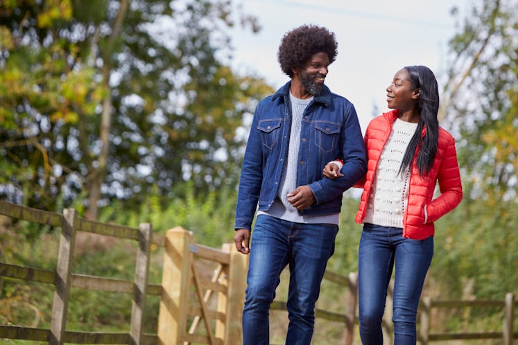 Black adult couple talking and walking  arm in arm in the countryside
