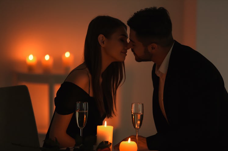 Young couple kissing while sitting at table with burning candles