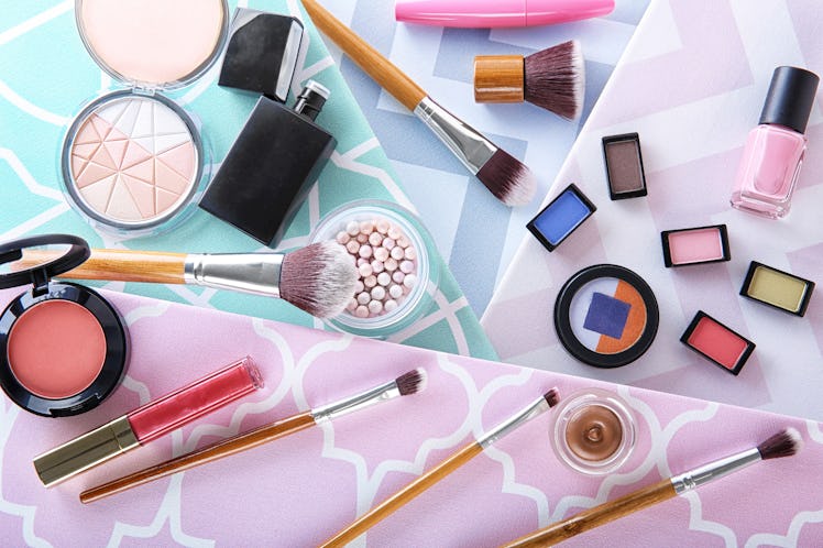 Cosmetic products and brushes on colorful background