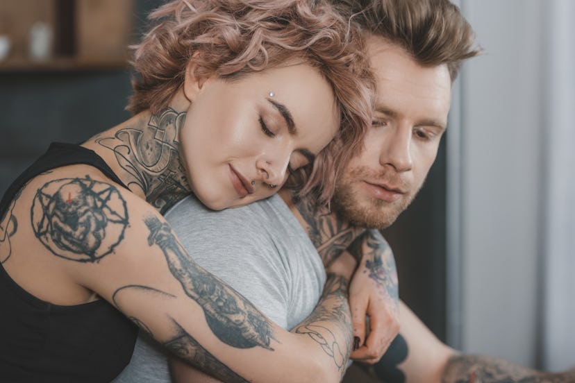 young tattooed couple hugging with closed eyes