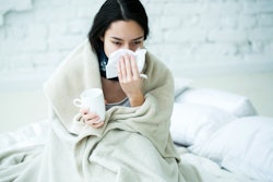 Young woman sick with temperature drinks hot 