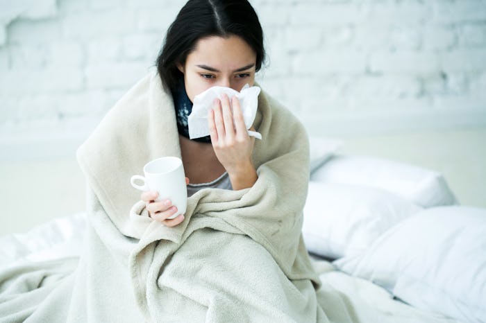 Young woman sick with temperature drinks hot