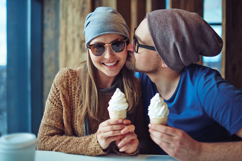 Young man kissing his girlfriend while having ice-cream