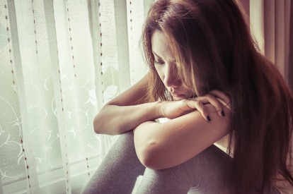 young sad woman sit beside window with vintage filter effect