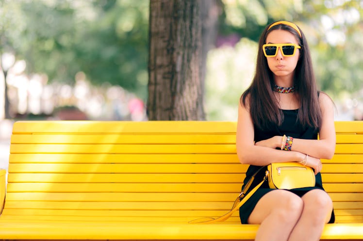 Bored Woman Waiting for her Date Alone on a Bench. Funny girlfriend waiting for her boyfriend out in...