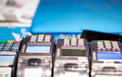 Close up of credit card payment terminal with blurred background in shopping mall. Various credit ca...