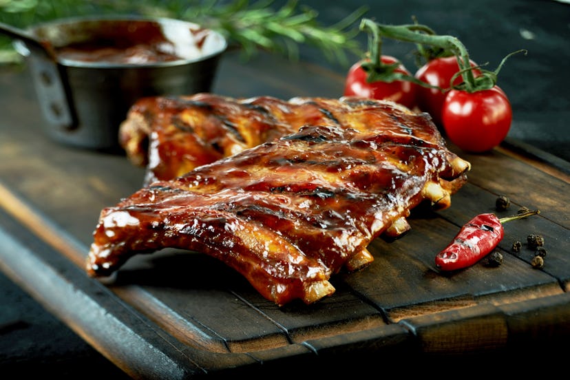 Spicy hot grilled spare ribs from a summer BBQ served with a hot chili pepper and fresh tomatoes on ...