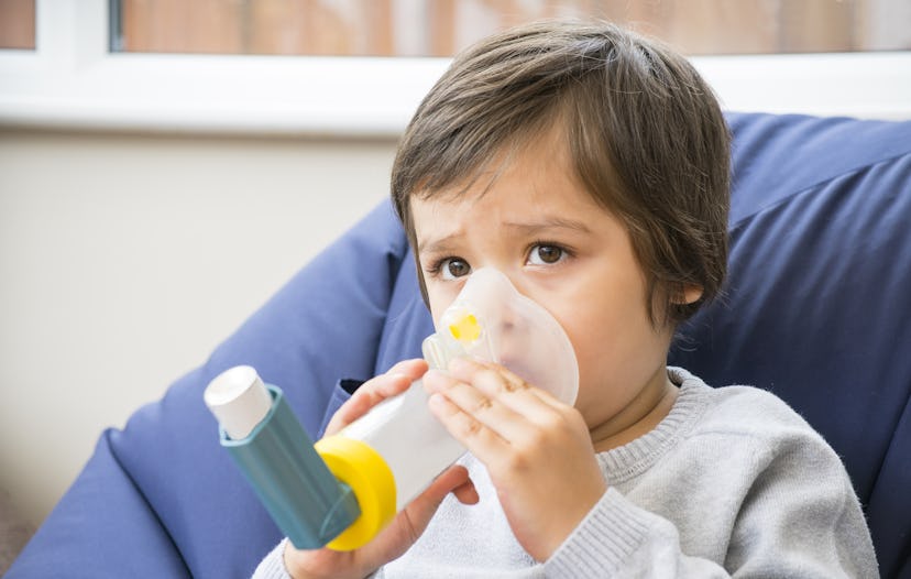 A boy have a problem with chest coughing holding inhaler mask by him self, Kid using the volumtic fo...