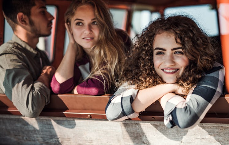 A group of young friends on a roadtrip through countryside, looking out of window.