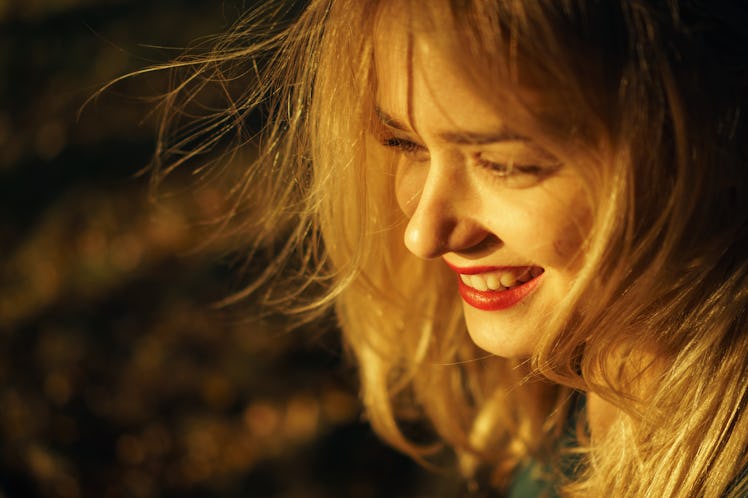 Autumn portrait of young happy smiling girl with red lips at sunset