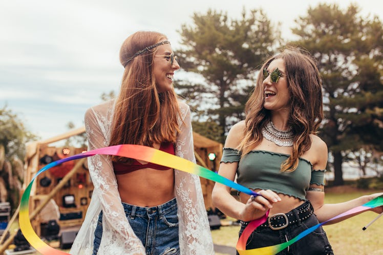 Hipsters with dancing ribbon stick at music festival. Two young women enjoying at music festival.