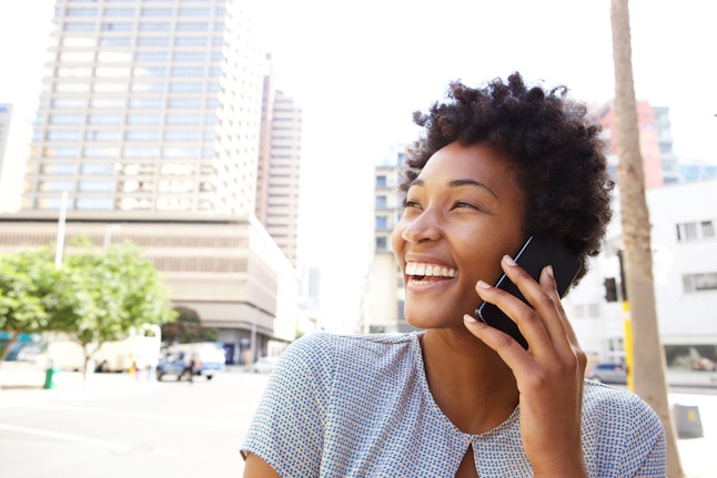 Closeup portrait of a cheerful young woman making a phone call outdoors in the city 
