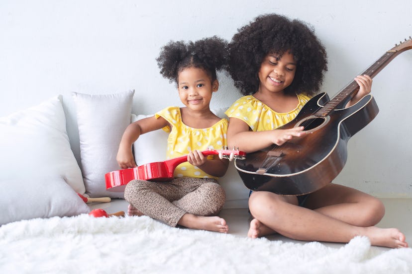 Two sisters are sitting and playing guitar on the floor in a round up of Instagram captions for Nati...