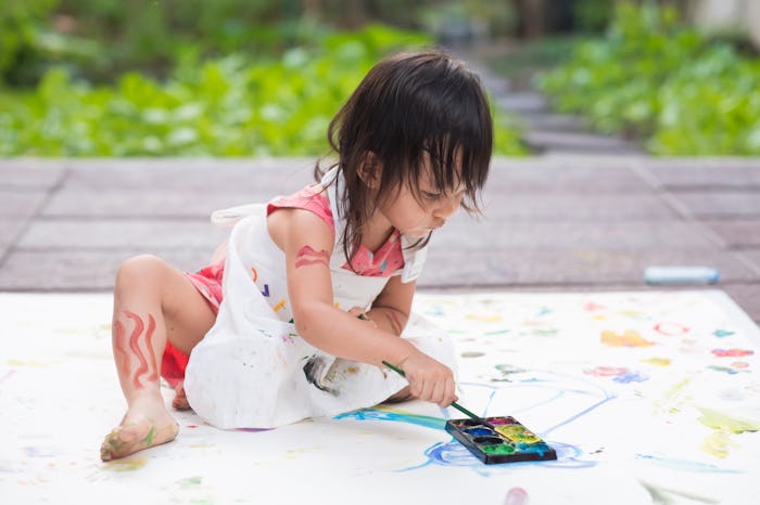 Adorable asian little girl is playing by painting water color outside the house, concept of art educ...