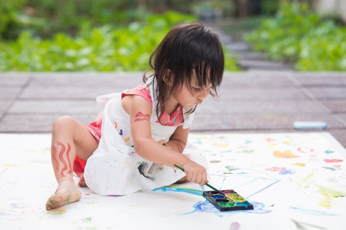 Adorable asian little girl is playing by painting water color outside the house, concept of art educ...