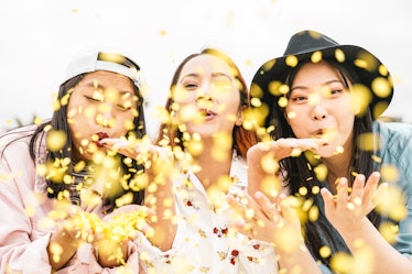 Happy Asian friends doing party throwing confetti outdoor - Young people having fun celebrating at f...