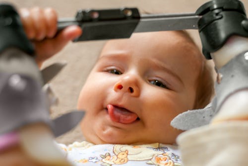 A nine month old baby with a tongue tie and orthopedic shoes lays on her back with her tongue sticki...