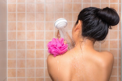 Portrait of beautiful woman taking shower with bath sponge.