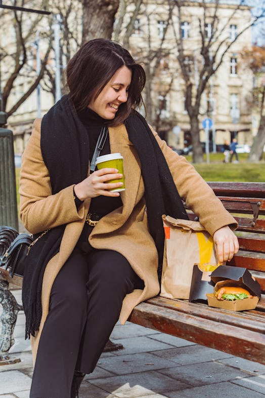 woman eating fast food on city bench. lifestyle concept